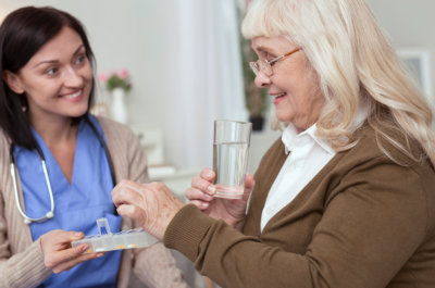 female nurse giving medicine to senior woman