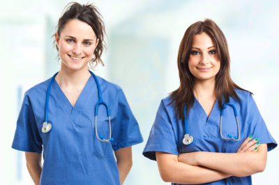 two nurses wearing scrubs smiling